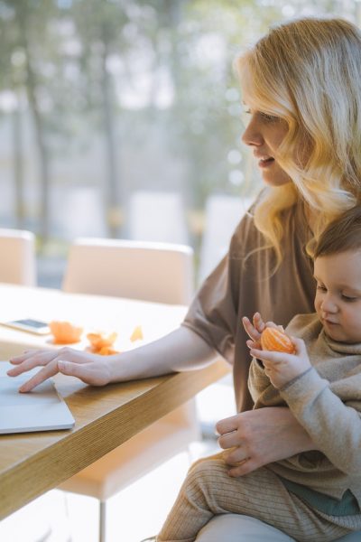 woman carrying her baby and working on a laptop 4079281